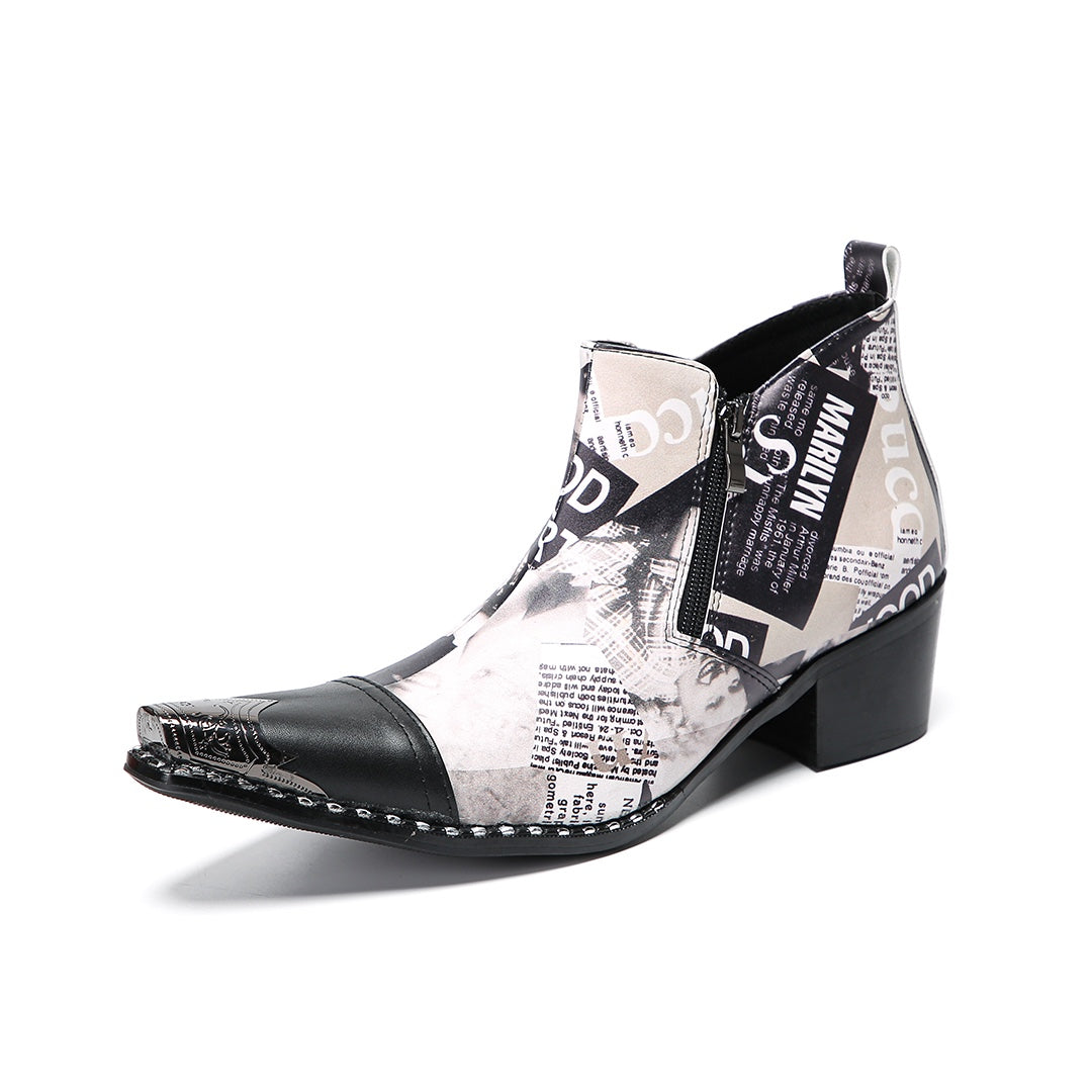 A pair of men's black and white newspaper print ankle boots with a pointed metal toe, side zipper, and block heel.