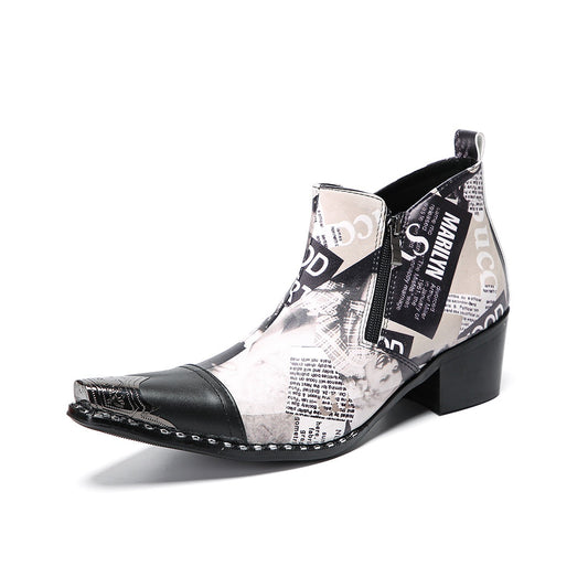 A pair of men's black and white newspaper print ankle boots with a pointed metal toe, side zipper, and block heel.