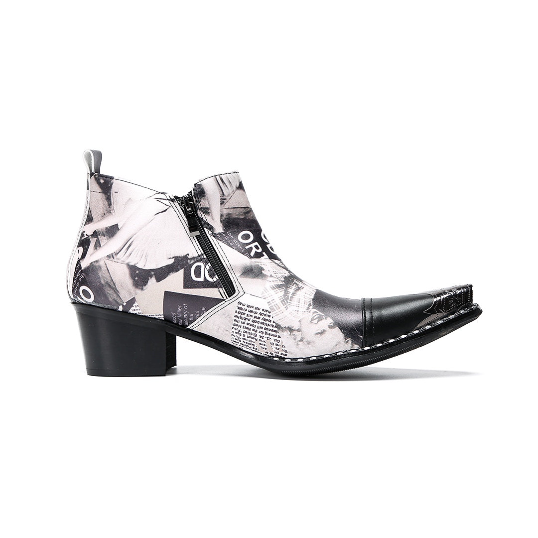 A pair of men's black and white newspaper print ankle boots with a pointed metal toe, side zipper, and block heel.