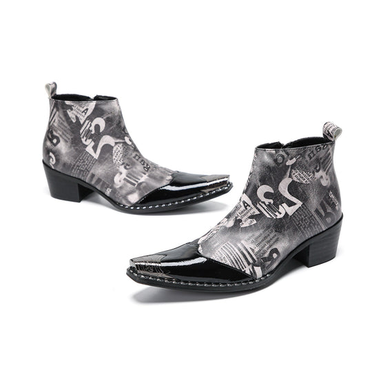 Pair of men's black and white newspaper print ankle boots with patent leather pointed toes and studded details.