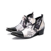 A pair of men's black and white newspaper print ankle boots with a pointed metal toe, side zipper, and block heel.