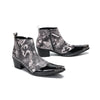 Pair of men's black and white newspaper print ankle boots with patent leather pointed toes and studded details.