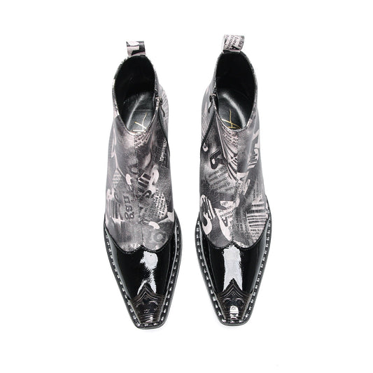 Pair of men's black and white newspaper print ankle boots with patent leather pointed toes and studded details.