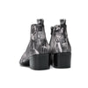 Pair of men's black and white newspaper print ankle boots with patent leather pointed toes and studded details.