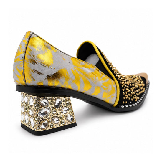 A pair of men's black studded loafers with a gold metal toe cap, a gold and grey patterned upper, and a crystal-embellished
