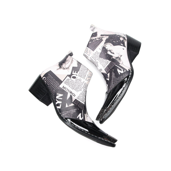 Pair of Aomishoes men's newspaper print ankle boots with pointed patent leather toe caps and side zippers on a white