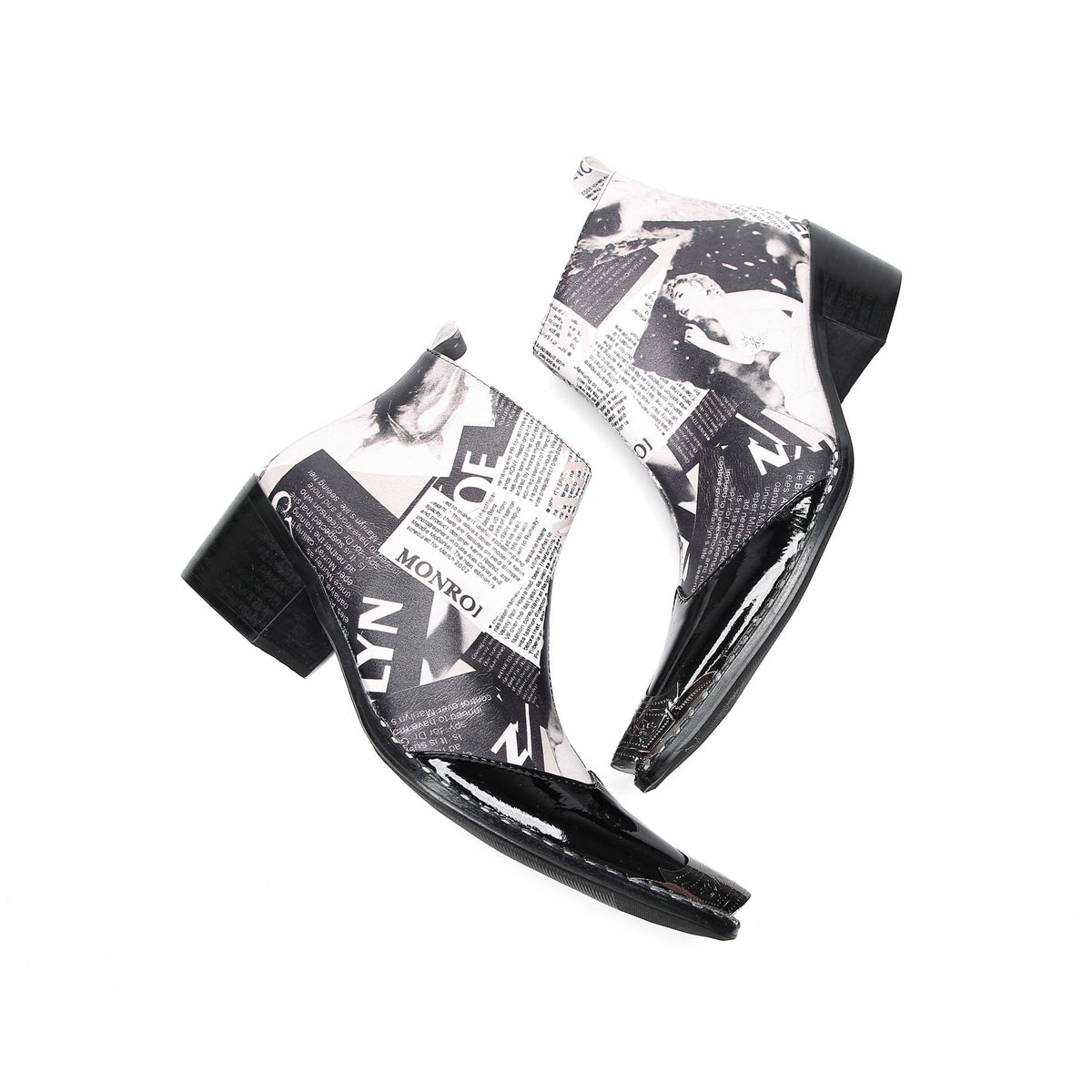 Pair of Aomishoes men's newspaper print ankle boots with pointed patent leather toe caps and side zippers on a white