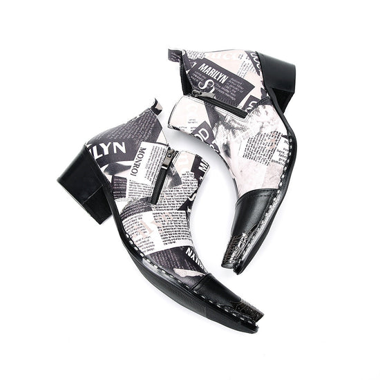 A pair of men's black and white newspaper print ankle boots with a pointed metal toe, side zipper, and block heel.