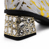 White and gold foil patterned ankle boot with a pointed metal toe, side zipper, and a block heel embellished with clear